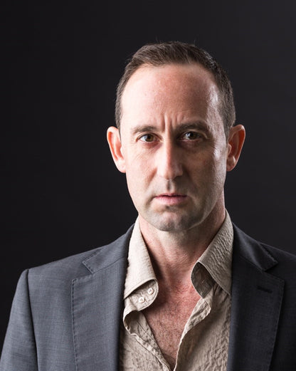 Man wearing a dark suit over a light shirt against a black background