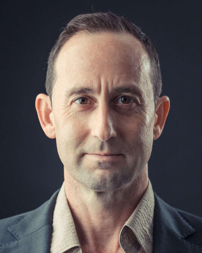 Man wearing a dark jacket over a light shirt against a black background